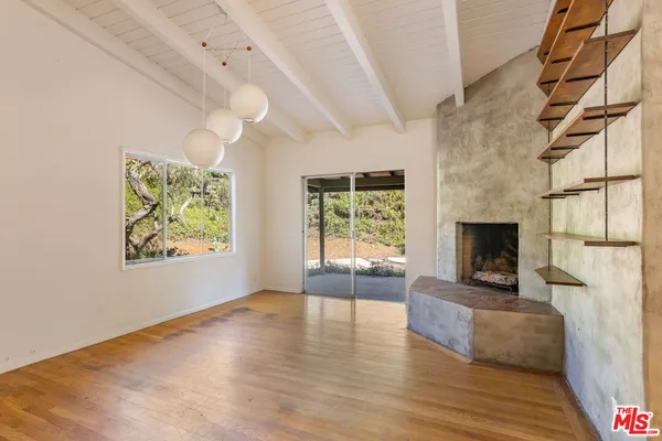 a view of a livingroom with wooden floor a fireplace and windows