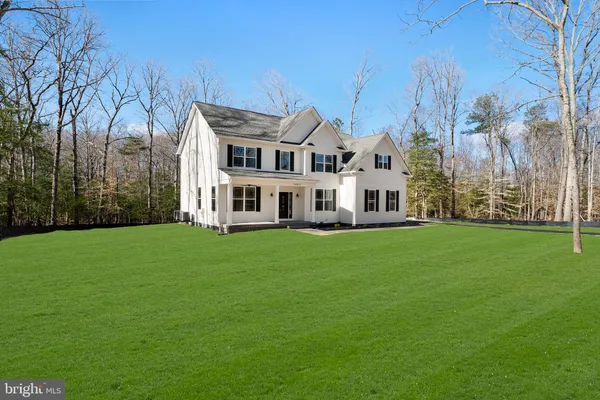 a view of a white house in front of a big yard with large trees