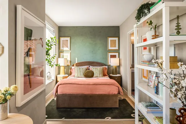 a bedroom with a bed a bookshelf and a potted plant