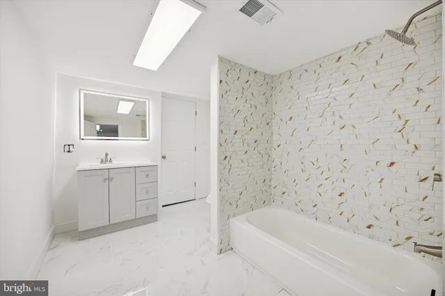 a bathroom with a bathtub sink vanity and mirror