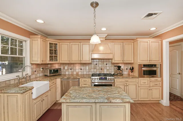 a kitchen with kitchen island granite countertop a sink a counter top space appliances and cabinets