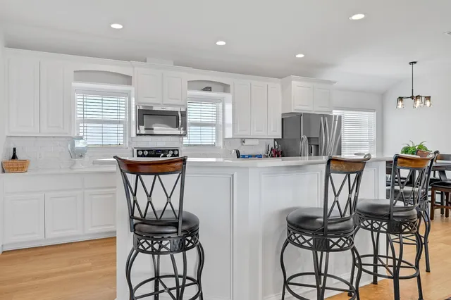 a kitchen with stainless steel appliances a dining table chairs stove refrigerator and cabinets
