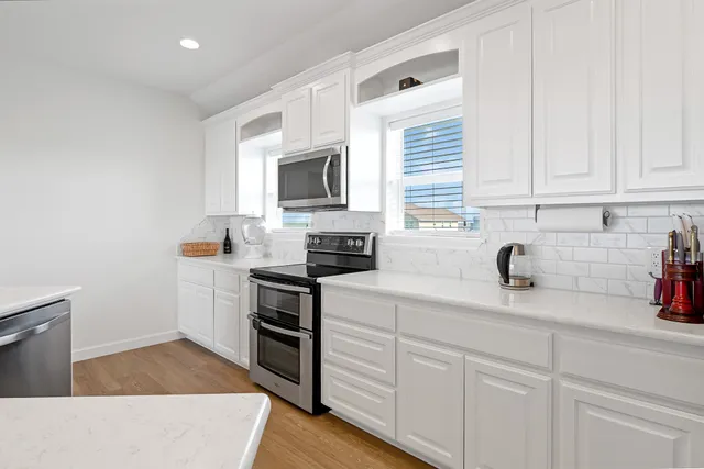 a kitchen with stainless steel appliances granite countertop grey cabinets a stove a sink and dishwasher