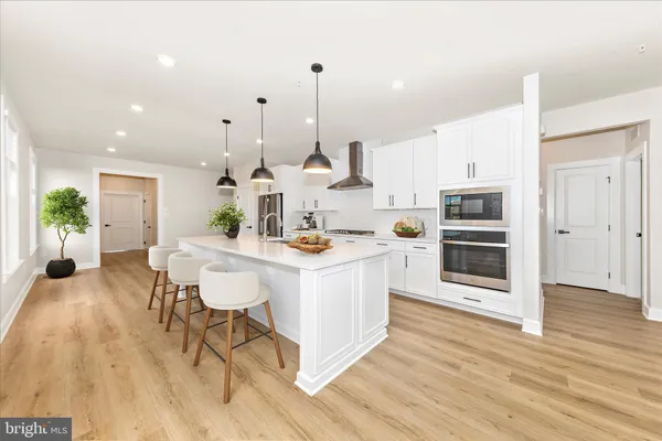 a kitchen with stainless steel appliances kitchen island wooden floors and white cabinets