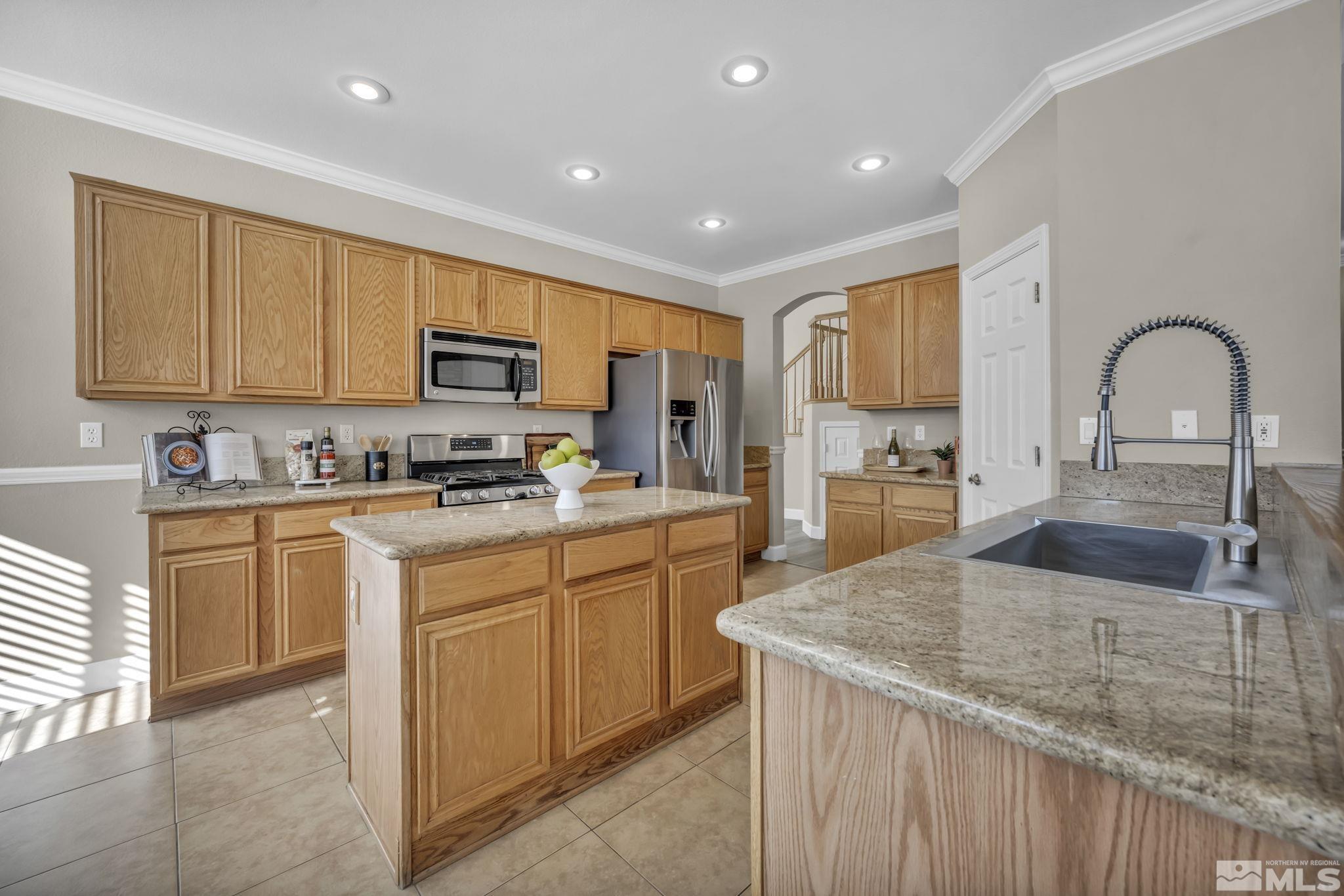 9765 Rolling Rock Court Reno, NV 89521 - Photo 10 of 39 a kitchen with granite countertop a stove top oven a sink dishwasher and white cabinets with wooden floor