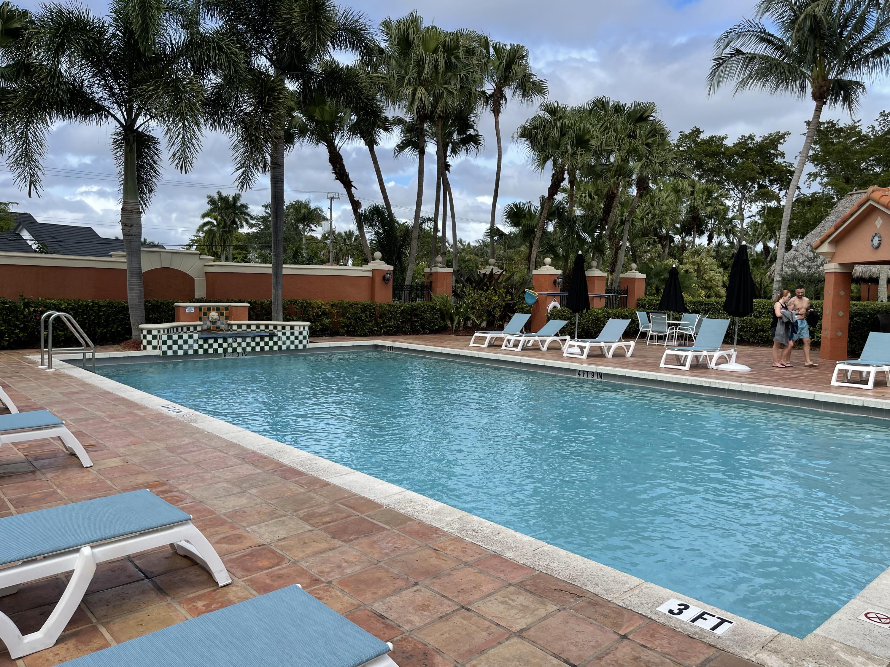 3111 Clint Moore Road, Unit 205 Boca Raton, FL 33496 - Photo 34 of 35 a view of a swimming pool with a table and chairs