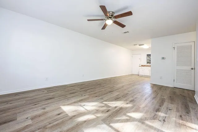 an empty room with wooden floor and a ceiling fan