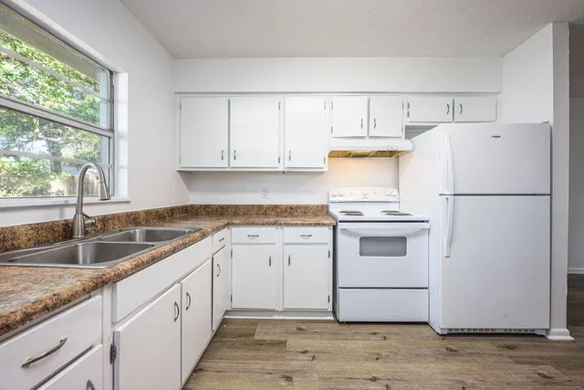 a kitchen with granite countertop white cabinets and white appliances