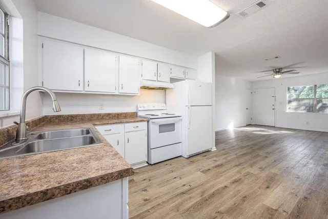 a kitchen with granite countertop a sink stainless steel appliances and white cabinets