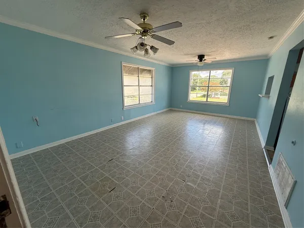 an empty room with windows and fan