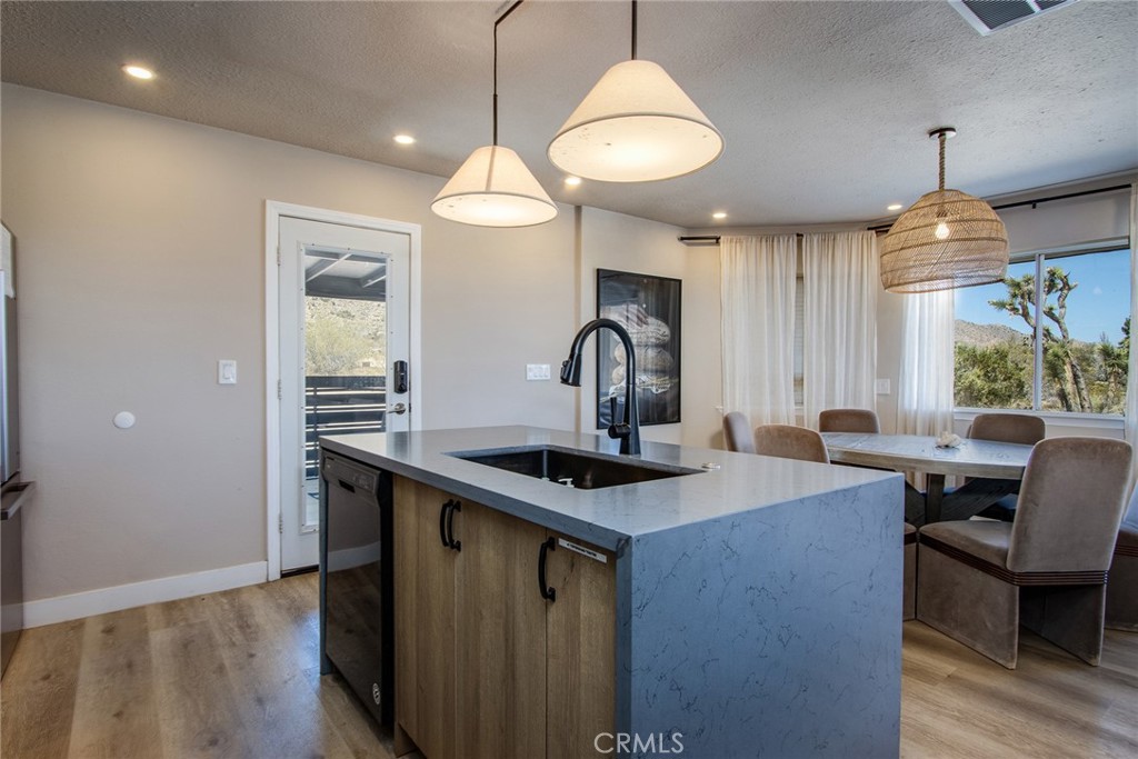 9073 Tortuga Trail Joshua Tree, CA 92252 - Photo 12 of 39 a kitchen with kitchen island a dining table chairs sink and wooden floor