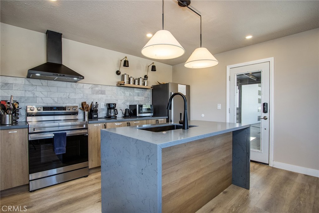 9073 Tortuga Trail Joshua Tree, CA 92252 - Photo 9 of 39 a kitchen with stainless steel appliances granite countertop a sink a stove and a wooden floors