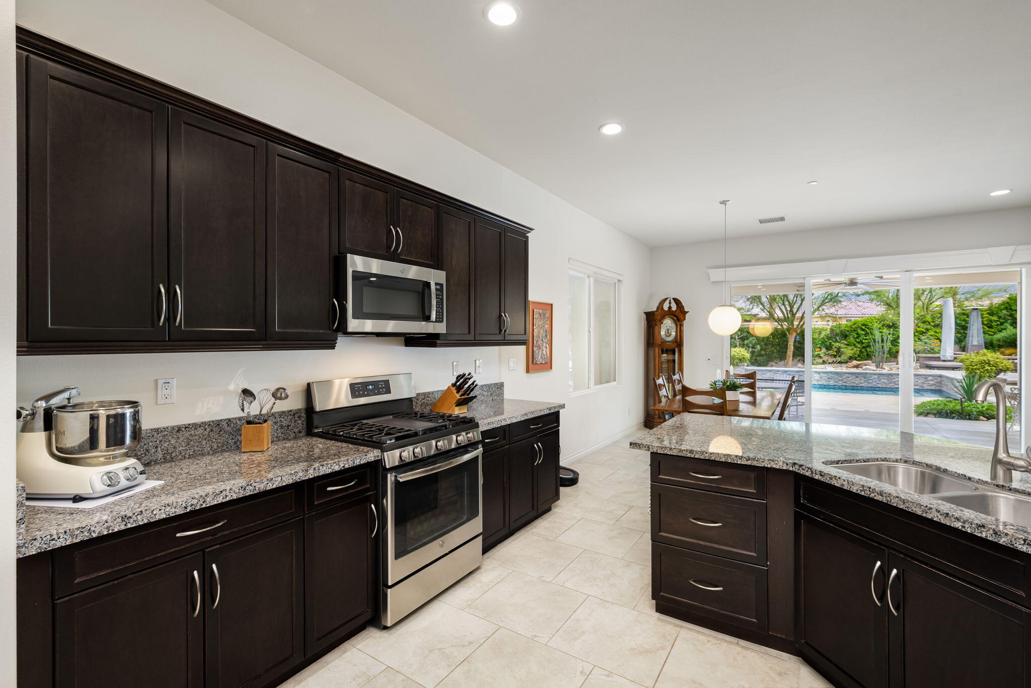85568 Brovello Drive Indio, CA 92203 - Photo 13 of 50 a kitchen with granite countertop a sink dishwasher stove and microwave with wooden cabinets