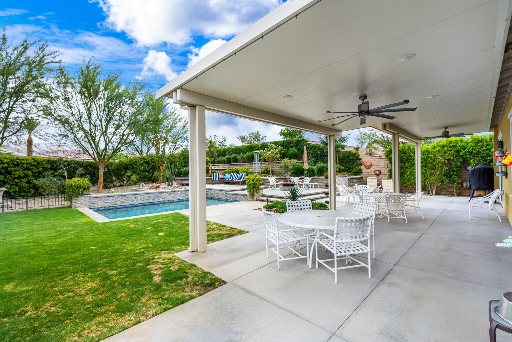 85568 Brovello Drive Indio, CA 92203 - Photo 43 of 50 a view of a patio with a table and chairs under an umbrella next to a yard