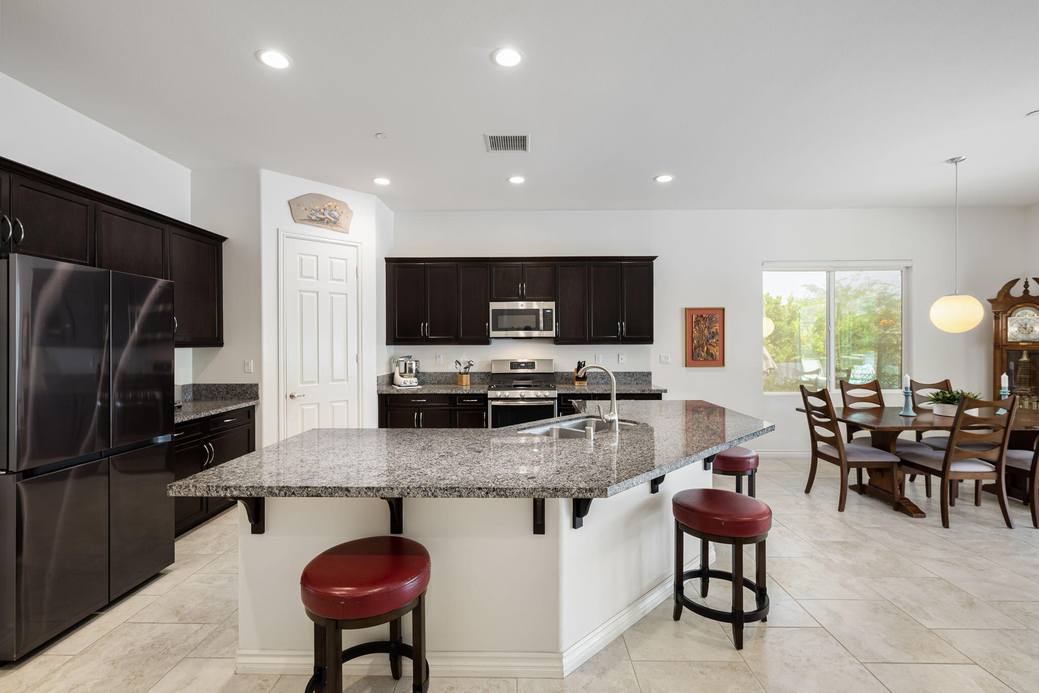 85568 Brovello Drive Indio, CA 92203 - Photo 7 of 50 a kitchen with stainless steel appliances kitchen island granite countertop a table chairs sink refrigerator and microwave