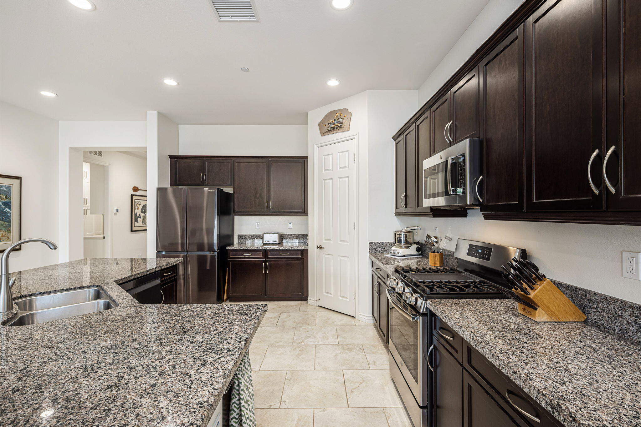 85568 Brovello Drive Indio, CA 92203 - Photo 10 of 50 a kitchen with stainless steel appliances granite countertop a stove top oven microwave and refrigerator