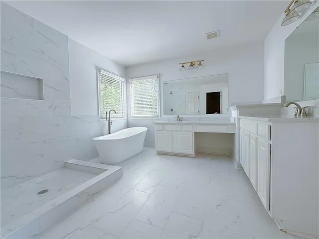 a bathroom with a double vanity sink a mirror and a bathtub