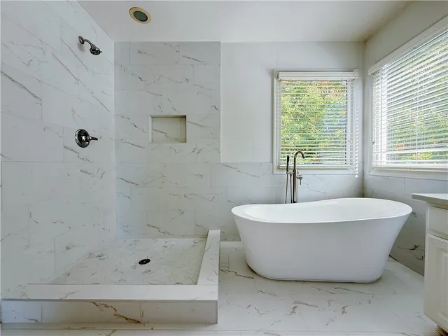 a white bath tub sitting in a bathroom next to a window