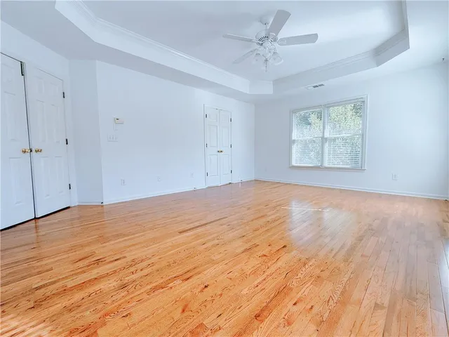a view of an empty room with a window and wooden floor