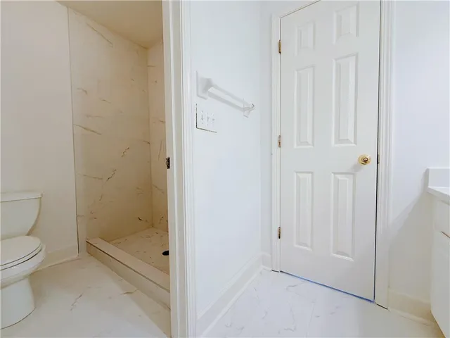 a bathroom with a granite countertop toilet a sink and shower