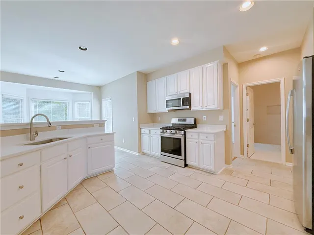 a kitchen with white cabinets a sink and appliances