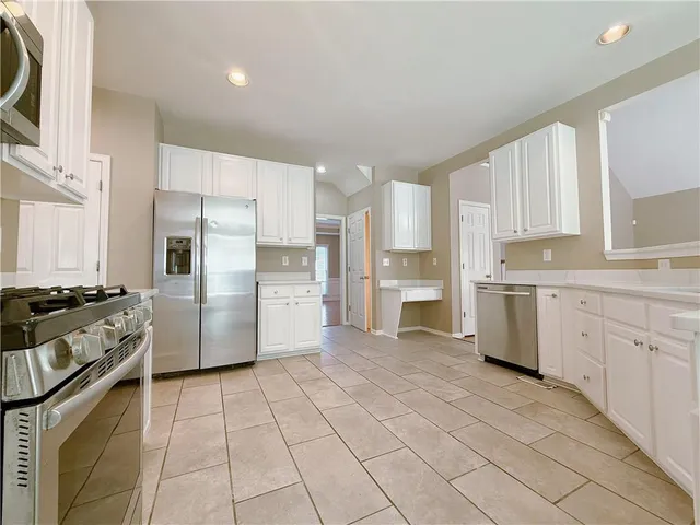 a kitchen with white cabinets and appliances