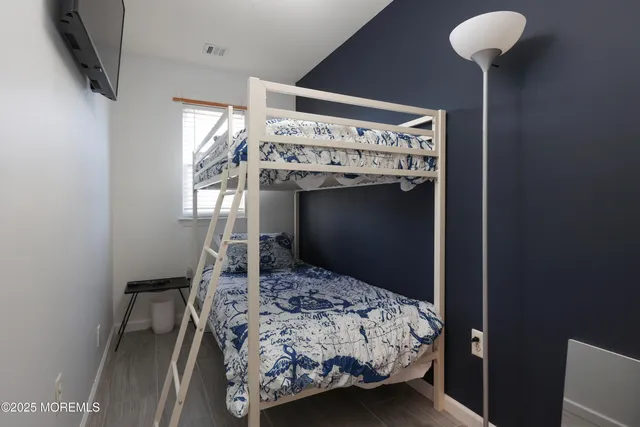 a spacious bedroom with a bed and a flat tv screen on wall