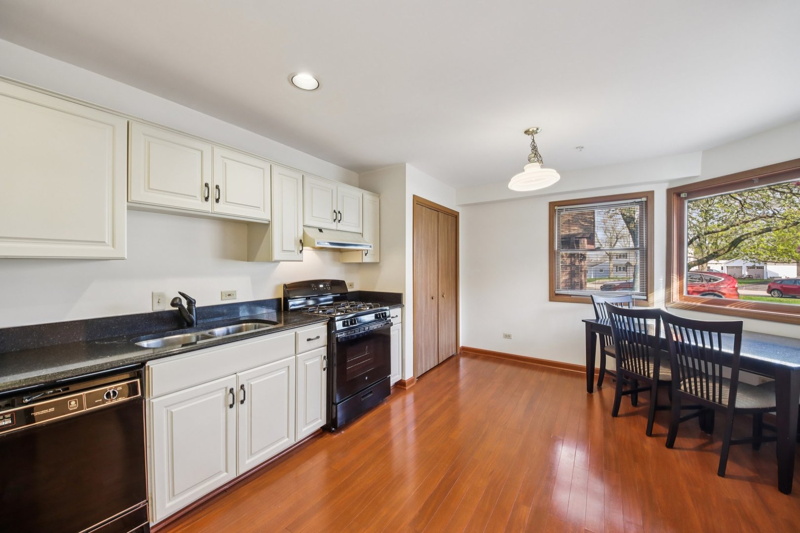 37 Terrace Lane, Unit F Lake Zurich, IL 60047 - Photo 13 of 40 a kitchen with granite countertop a stove top oven a sink a dining table and chairs with wooden floor