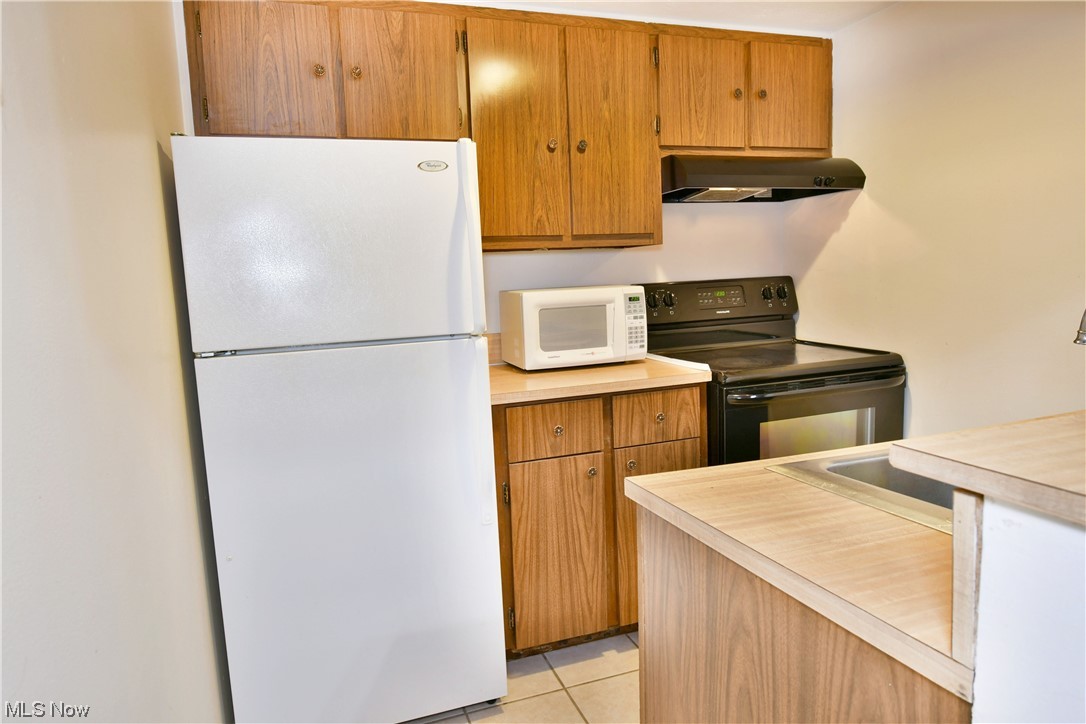 2980 North River Road Northeast, Unit E3 Warren, OH 44483 - Photo 5 of 27 Kitchen with light tile floors, white appliances, and wall chimney exhaust hood
