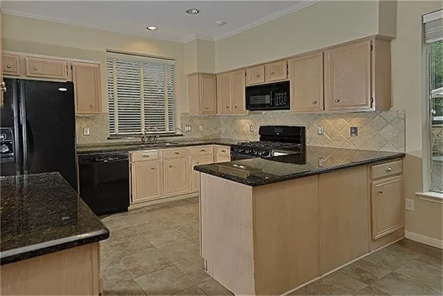 a kitchen with granite countertop stainless steel appliances a sink stove and refrigerator