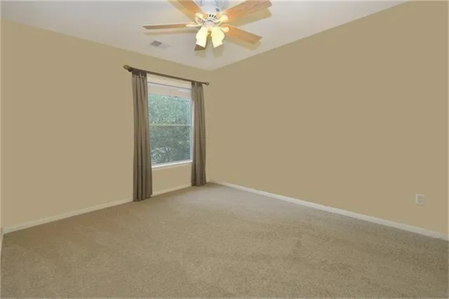 an empty room with a window and a fan