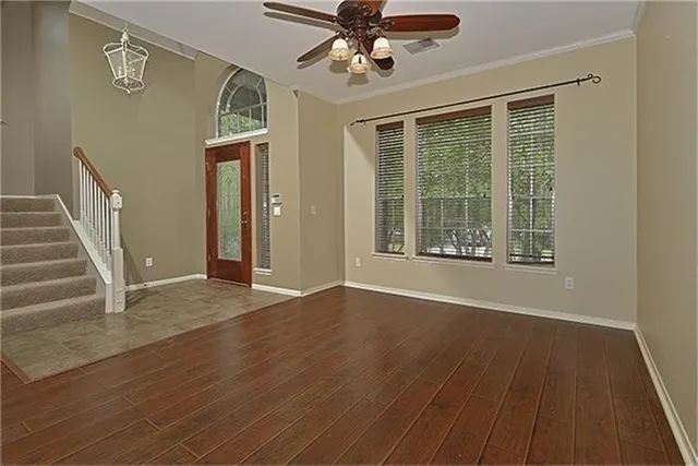 a view of an empty room with wooden floor and a window