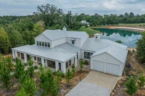an aerial view of a house with a yard and a pond
