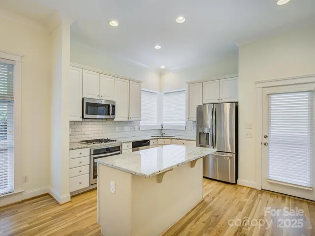 a kitchen with stainless steel appliances granite countertop a sink a stove a refrigerator and cabinets