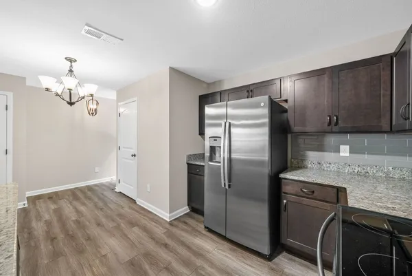 a kitchen with stainless steel appliances granite countertop a refrigerator a sink dishwasher a stove with wooden cabinets and floor