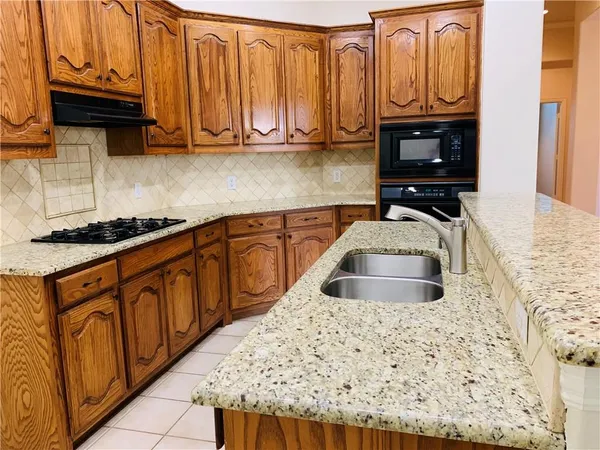 a kitchen with granite countertop cabinets and black appliances