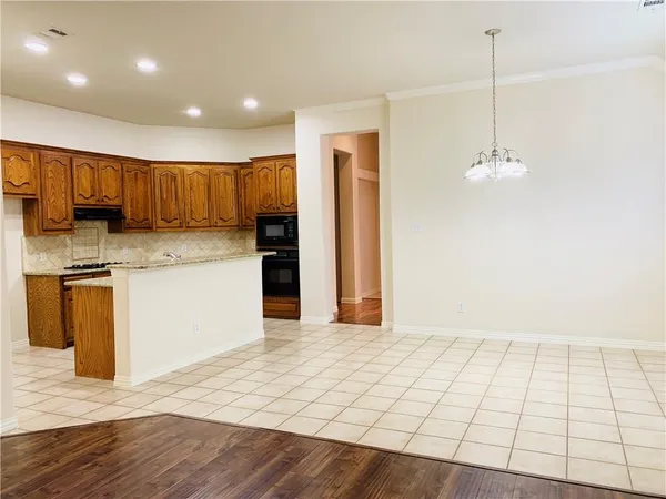a kitchen with kitchen island granite countertop wooden cabinets and a refrigerator