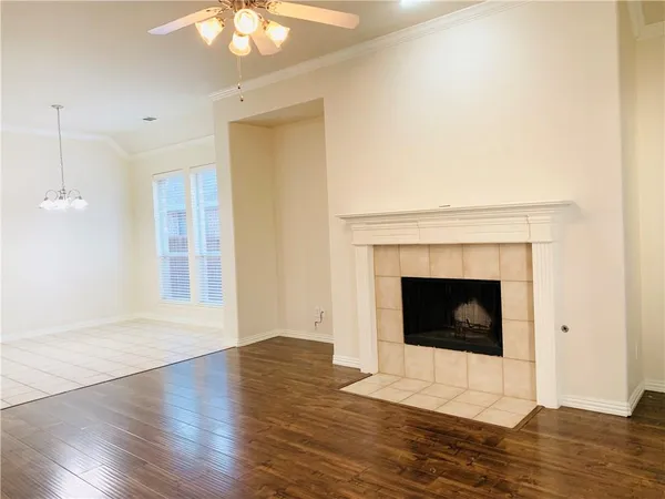 a view of an empty room with wooden floor and a fireplace