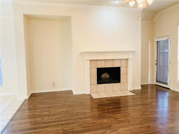 a view of an empty room with wooden floor and a fireplace