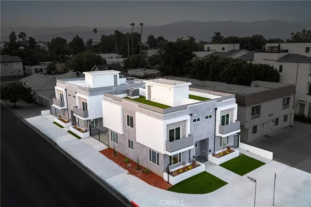 a view of a house with a small yard and a large tree