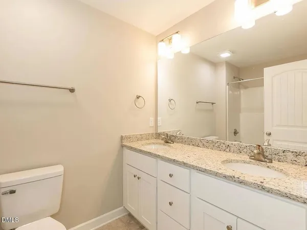a bathroom with a granite countertop sink a mirror and a toilet