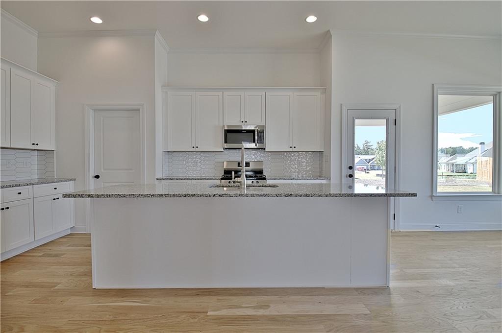 115 Rutland Court Senoia, GA 30276 - Photo 19 of 69 a kitchen with stainless steel appliances granite countertop a stove a sink and white cabinets