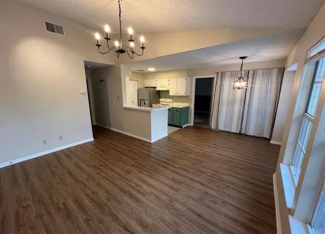 a view of a hallway with wooden floor and a kitchen