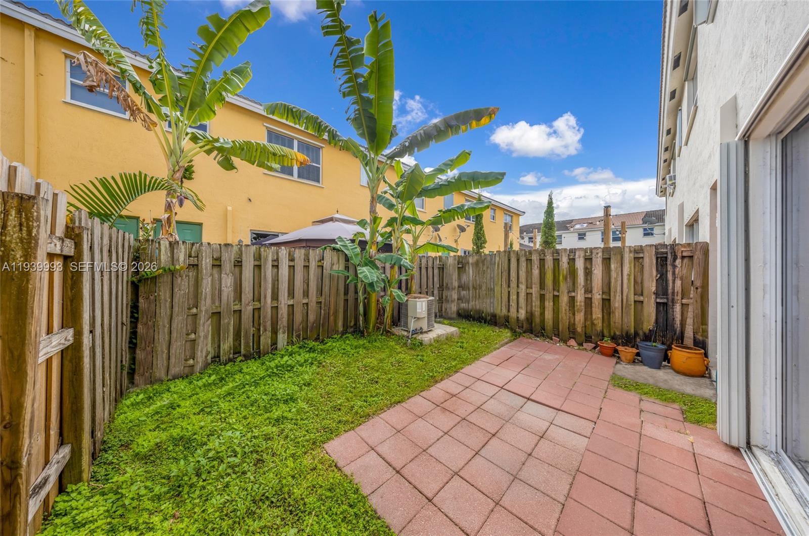 951 Northeast 42nd Terrace, Unit 951 Homestead, FL 33033 - Photo 29 of 30 a view of a backyard with brick wall and potted plants