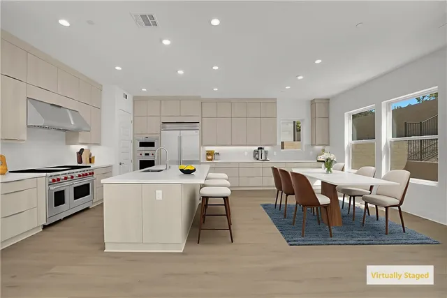 a large white kitchen with lots of furniture a counter top space a sink stainless steel appliances and cabinets