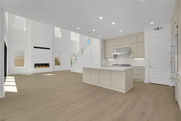 a large white kitchen with kitchen island a sink a stove a refrigerator and white cabinets