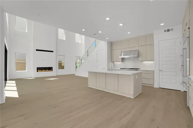 a large white kitchen with kitchen island a sink a stove a refrigerator and white cabinets