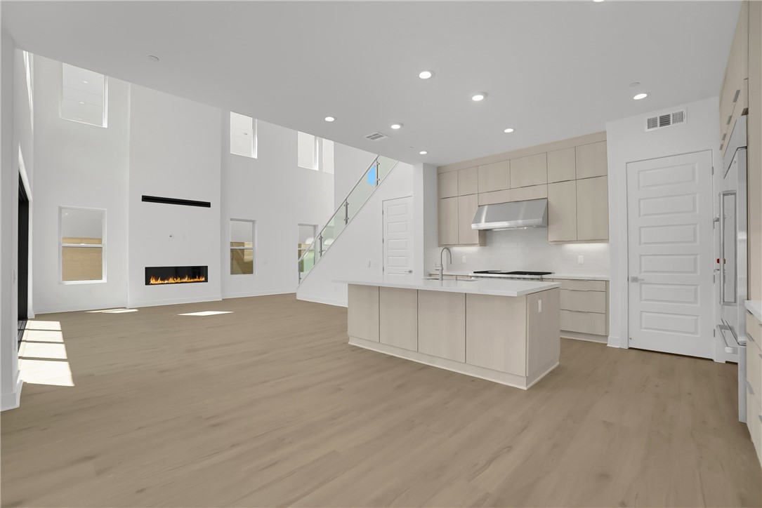 168 Creation Irvine, CA 92618 - Photo 13 of 59 a large white kitchen with kitchen island a sink a stove a refrigerator and white cabinets