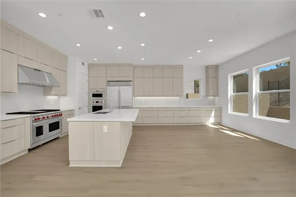 a large kitchen with stainless steel appliances a large counter top and a stove top oven