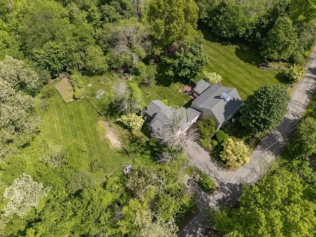 an aerial view of residential house with outdoor space and trees all around
